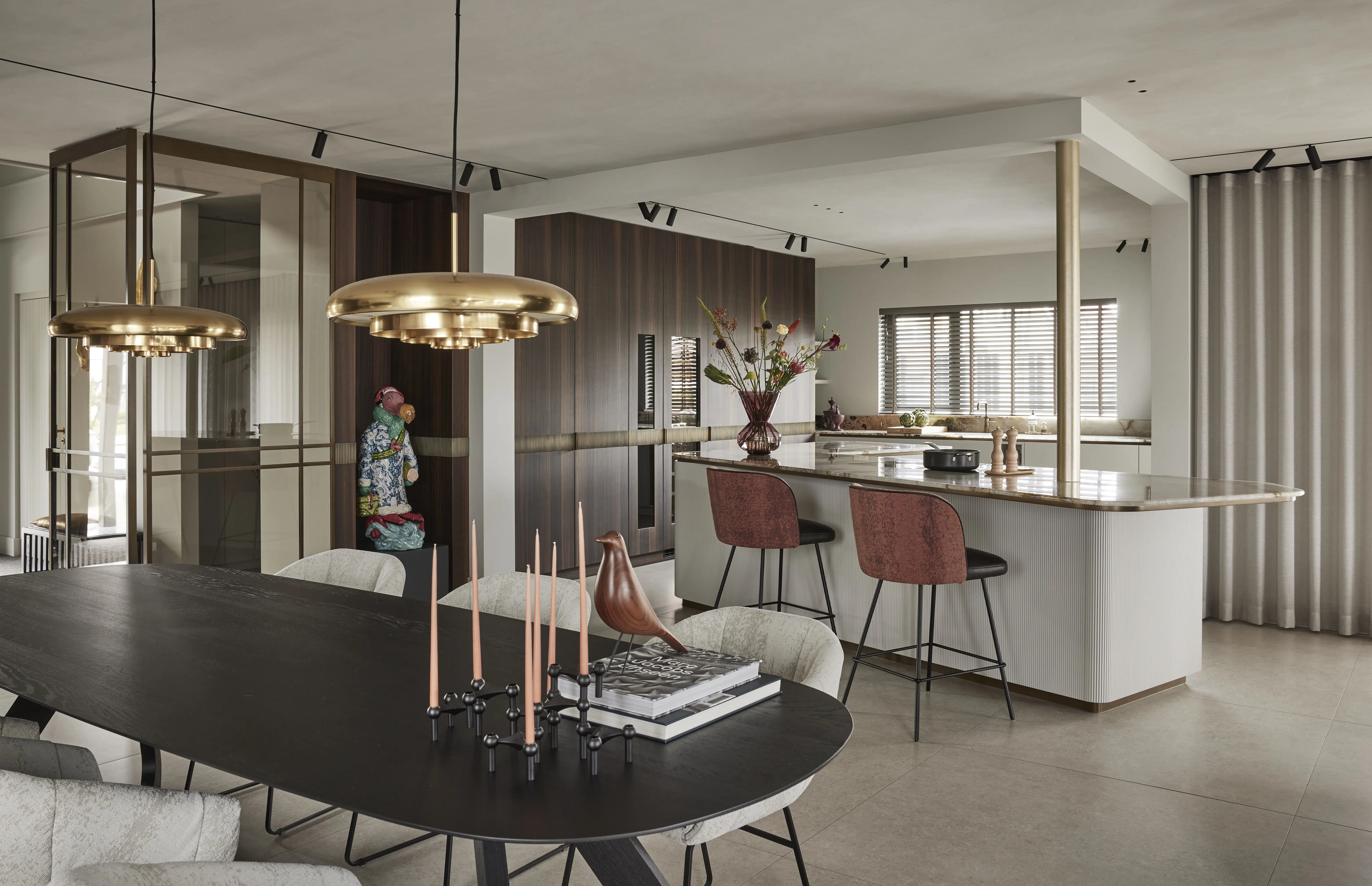 luxe interieur ontworpen door ENZO architecten met brass lampen een grote zwarte tafel en en houten keukenkastjes